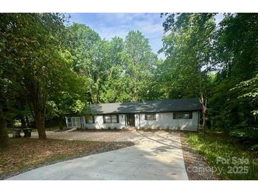 A charming single-story home features a long driveway and a private setting surrounded by lush trees at 217 Ruby Ln, Gastonia, NC 28054