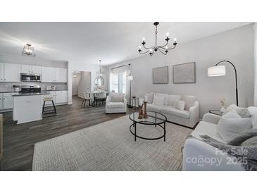 Open concept living room features a white sofa, kitchen with island, and dining area at 224 Briana Marie Way, Indian Trail, NC 28079