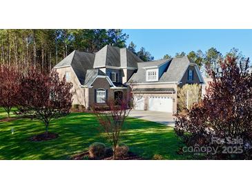 Beautiful two-story brick home featuring a manicured lawn, mature trees, and a three-car garage at 407 Blue Bay Ct, York, SC 29745