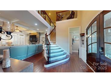 Grand foyer with wood floors, staircase, and view into the living room with a stone fireplace at 407 Blue Bay Ct, York, SC 29745