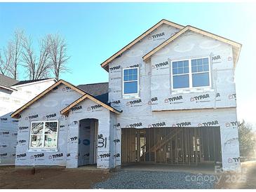 New construction home featuring a two-car garage, modern windows and protective Typar building wrap at 9842 Quercus Ln, Huntersville, NC 28078