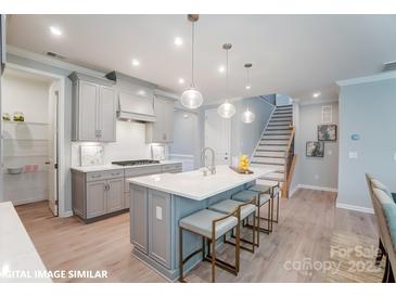 Modern kitchen with island, stainless steel appliances, and light gray cabinets at 9842 Quercus Ln, Huntersville, NC 28078