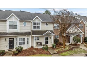 Tan two-story townhome with a covered porch and landscaping at 12250 Savannah Garden Dr, Charlotte, NC 28273