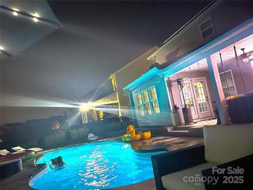 Inviting backyard pool featuring outdoor seating, inflatable toys, and ambient lighting for evening enjoyment at 2262 Galloway Sw Ln, Concord, NC 28025