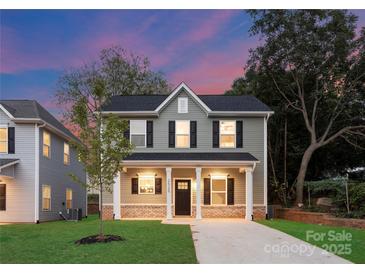 Charming two-story home with green siding, black shutters, and a well-manicured lawn at dusk at 2033 Tom Sadler Rd, Charlotte, NC 28214