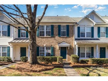 Brick townhome with 2-story facade, green trim, and landscaping at 7117 Flying Scotsman Dr, Charlotte, NC 28213