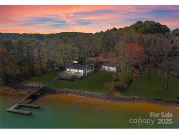 Stunning lakefront estate with private dock and lush landscaping at sunset offers serene waterfront living at 125 Chestnut Tree Rd, Mooresville, NC 28117