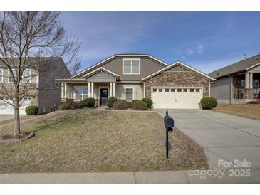 Charming home featuring a manicured lawn, stone accents, and an attached two car garage at 2001 Yellow Daisy Dr, Matthews, NC 28104