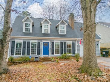 Gray house with blue door, shutters, and landscaping; two-story home with a gray roof at 8708 Sweet Sage Ln, Charlotte, NC 28227