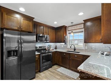 Spacious kitchen featuring dark wood cabinets, granite countertops, and stainless steel appliances at 130 Portman Ln, Statesville, NC 28625