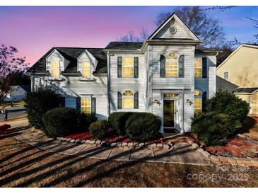 Charming two-story home with manicured landscaping, lush bushes, and warm inviting lighting at 9635 Veronica Dr, Charlotte, NC 28215