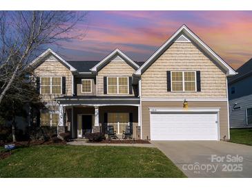 Charming two-story home featuring a manicured lawn, rocking-chair front porch, and attached two-car garage at 13618 Pacific Echo Dr, Charlotte, NC 28277