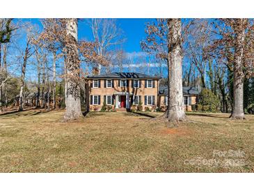 Brick house with red front door, nestled on a spacious lot with mature trees at 140 Kent Rd, Salisbury, NC 28147