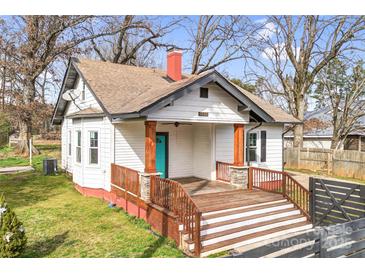 Exterior view of a cozy one-story home with a wooden porch and blue door, surrounded by trees at 8228 Moores Chapel Rd, Charlotte, NC 28214