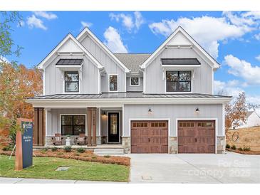 Two-story farmhouse exterior with gray siding, brown accents, and a two-car garage at Lot 113 Mayes Meadow Dr # Savanh, Cornelius, NC 28078