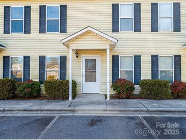 Light yellow siding townhouse with dark shutters, covered entry, and landscaping at 217 22Nd Sw St # H, Hickory, NC 28602