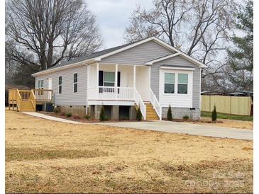 Charming gray home with white trim, a cozy front porch, and a freshly poured concrete driveway at 507 E Lackey Farm Rd, Stony Point, NC 28678