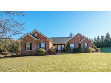 Brick ranch home with landscaped lawn and partial fence at 11304 Lemmond Acres Dr, Mint Hill, NC 28227