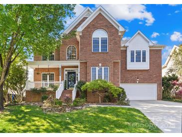 Charming two-story brick home boasts a well-manicured lawn and inviting front porch perfect for relaxing at 14500 Harvington Dr, Huntersville, NC 28078