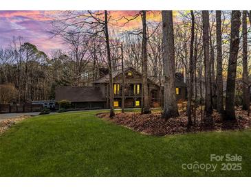 A warm home exterior featuring a lovely lawn, mature trees, and covered porches at dusk at 1703 Fairway Dr, Newton, NC 28658