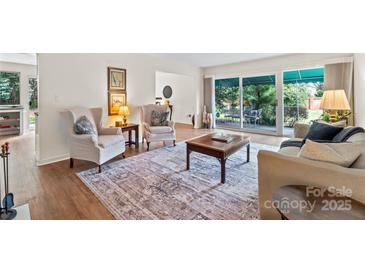 Bright living room with hardwood floors, comfortable seating, and sliding glass doors to the patio at 7000 Quail Hill Rd, Charlotte, NC 28210