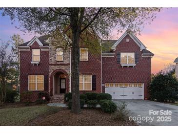 Brick two-story house with a three-car garage and landscaping at 14226 Carlton Woods Ln, Charlotte, NC 28278