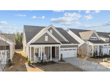Charming single-Gathering home featuring a covered front porch with rocking chairs and a two-car garage at 240 Portrait Way # 87, Indian Trail, NC 28079