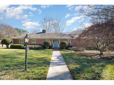 Brick ranch house with a light blue front door and landscaped lawn at 422 Roselawn Pl, Charlotte, NC 28211