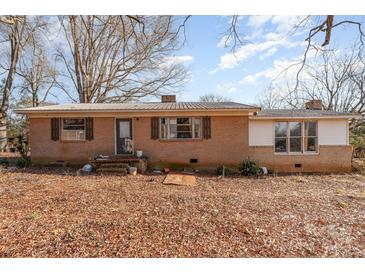 A quaint, one-story brick home with a metal roof, inviting entry, and surrounded by mature trees at 13501 Mullis Rd, Midland, NC 28107