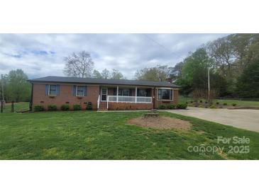 Charming single-story brick home with a covered front porch and well-manicured lawn and driveway at 5527 Dallas High Shoals Hwy Hwy, Dallas, NC 28034