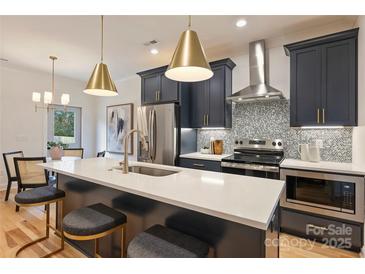 Modern kitchen featuring navy cabinets, stainless steel appliances, and a quartz countertop island with seating at 625 Colorado Ave # B, Charlotte, NC 28206