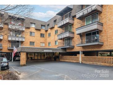 Brick condo building featuring a covered parking area, balconies, and well-maintained landscaping at 1323 Queens Rd # 312, Charlotte, NC 28207