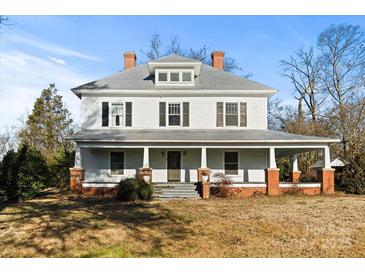 Two-story farmhouse with wrap-around porch and brick accents at 2948 W Main St, Claremont, NC 28610