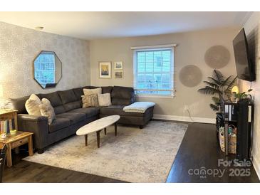 Spacious living room featuring a sectional sofa, large area rug, and stylish wall decor at 4923 Park Rd # D, Charlotte, NC 28209