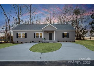 Charming single-story home features gray siding, black shutters, and a well-manicured front yard with a circular driveway at 7504 Surry Ln, Indian Trail, NC 28079