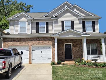 Charming two-story home with a brick facade, white trim, black shutters, and a two-car garage at 141 Silverspring Pl, Mooresville, NC 28117