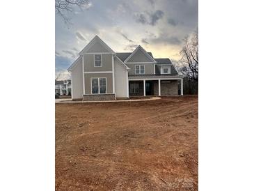 Two-story home with gray and beige siding, covered porch, and unfinished yard at 3428 Greene Rd, Monroe, NC 28110