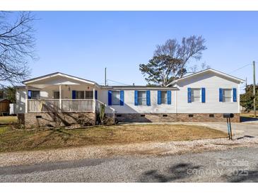 White doublewide home with blue shutters, a covered porch, and a landscaped yard at 111 Green Dr, Richburg, SC 29729