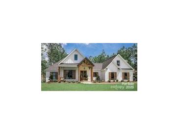 White farmhouse exterior with brown accents and a landscaped lawn at 295 Tradition Dr, Mount Gilead, NC 27306