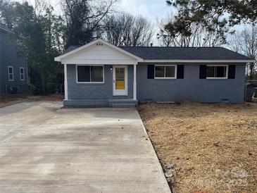 Newly renovated gray house with a yellow door, fresh landscaping, and a long driveway at 317 Echodale Dr, Charlotte, NC 28217