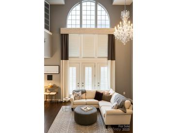 Bright living room with large windows, elegant chandelier, and comfortable seating area at 128 Steinbeck Way # E, Mooresville, NC 28117