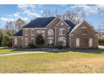 Stately brick home featuring a well-manicured lawn, arched windows, and a classic architectural design at 4316 Mourning Dove Dr, Matthews, NC 28104