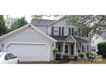 Two-story house with gray siding, a white garage door, and a front porch at 5711 Falls Ridge Ln, Charlotte, NC 28269