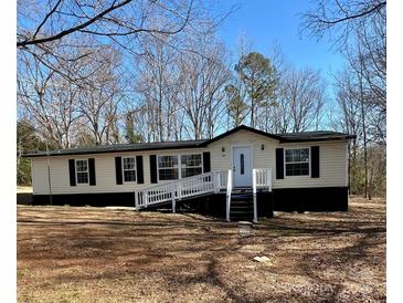 Charming single-story home with a ramp and traditional black shutters, set against a backdrop of mature trees at 137 S Penny St, Lancaster, SC 29720