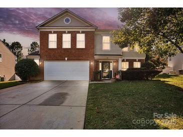 Brick two-story house with a two-car garage and landscaped lawn at 145 Ashton Woods Ct, Mount Holly, NC 28120