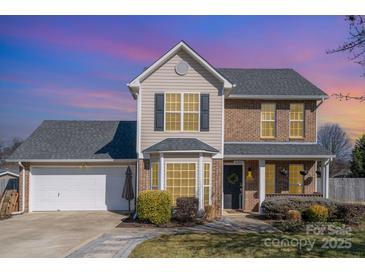 Brick two-story house with a gray roof, attached garage, and landscaped yard at 4301 Windjammer Sw Ct, Concord, NC 28027