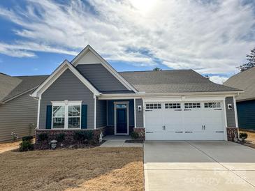 Charming single-story home with gray siding, a two-car garage, and well-manicured landscaping at 5047 Summer Surprise Ln, Charlotte, NC 28215