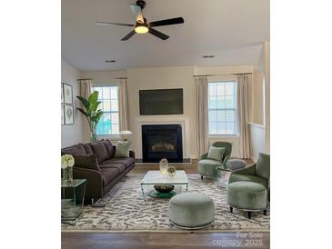 A beautifully furnished living room featuring a fireplace and modern ceiling fan at 6140 Whispering Brook Ct, Charlotte, NC 28216