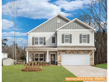 Two-story house with gray siding, stone accents, and a white garage door at 6332 Honor Ave, Midland, NC 28107