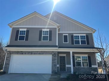 Charming two-story home with stone accents, gray siding, attached two car garage, and welcoming front porch at 6332 Honor Ave, Midland, NC 28107